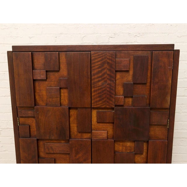A commanding vintage highboy armoire by Lane, defined by its dimensional mosaic of stacked and staggered wood blocks...