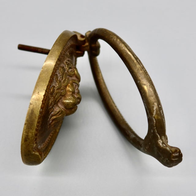 A classic English lion head door knocker in brass, with a full-maned lion set in a beaded oval frame and a hinged ring...