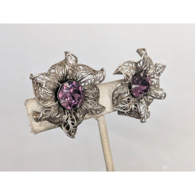 1950s silvertone filigree flowers with prong set round faux-amethyst centers clip earrings. Marked "NAPIER PAT. PEND."...