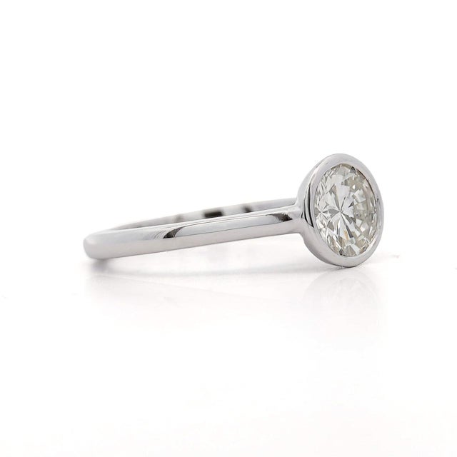 Natural 1.01 carat round brilliant diamond bezel set solitaire ring in 14K white gold featuring H-I color and SI1 clarity...
