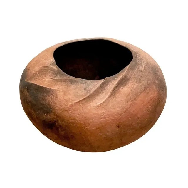 A terracotta pot with minimal elegant detailing. Fired clay with wave-like ripples at the mouth rim. Variance in color...