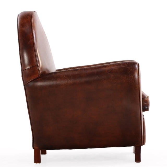 A handsome pair of early 20th-century Dutch leather club chairs with bold Art Deco styling. The design features dramatic...