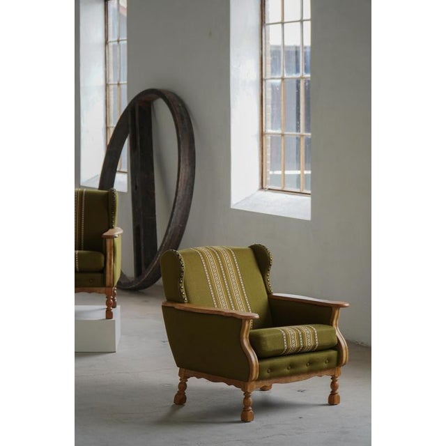 A charming pair of Danish lounge chairs crafted in solid oak and upholstered in their original green fabric with...