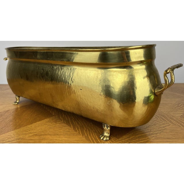 A beautifully crafted Vintage brass plant pot with an elegant elongated jardiniere shape, decorative side handles, and...
