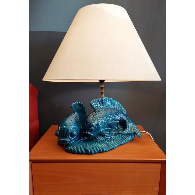 Table lamp made of enameled ceramic depicting two blue/blue koi carpes (dimensions of l40 x w43 x h35 cm). The support of...