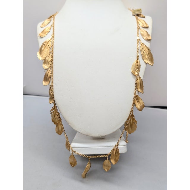 Goldtone feathers charm long necklace with spring ring clasp. Marked "Napier" in script on a plaque that the spring ring...