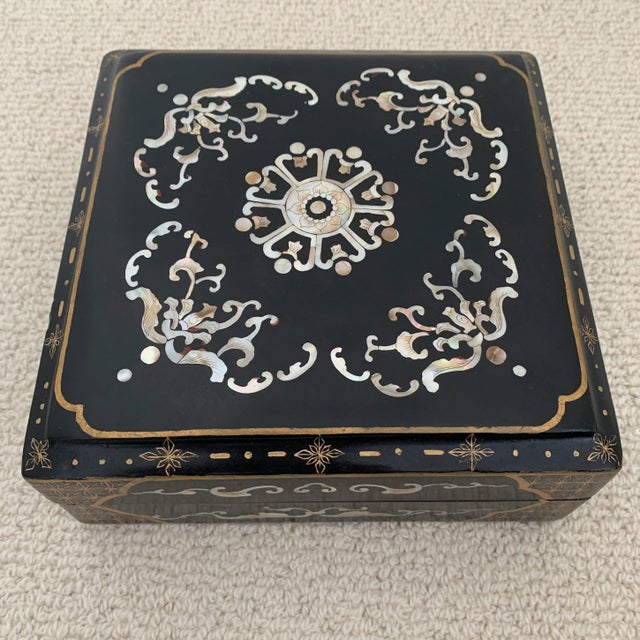 Black chinoiserie papier-mâché box. Lovely detailed top inlaid with mother of pearl. Gilt painted details on top and...