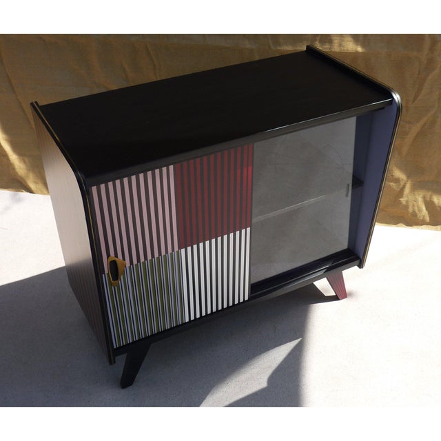Vintage chest of drawers with one sliding door in a PU lacquered finish and one sliding glass door with a gold-tone...