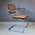 Cantilever chair S64 features a tubular metal frame, a wood and rattan backrest and seat and wooden armrests. This chair...
