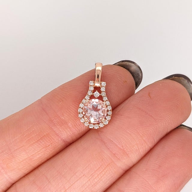 A morganite glows with pink brilliance at the heart of this round pendant, framed by a trail of brilliant natural...