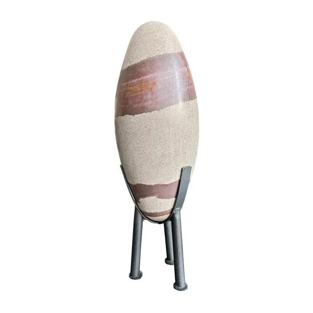 Oblong quartz rock of light grey body with large rusty brown inclusions. Shiva Lingam stones are ancient and gathered from...