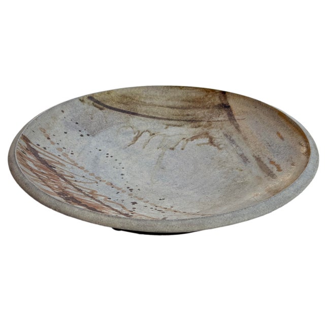 A modernist mid-century stoneware charger signed. On the bottom it is signed and has a hook for hanging on a wall....