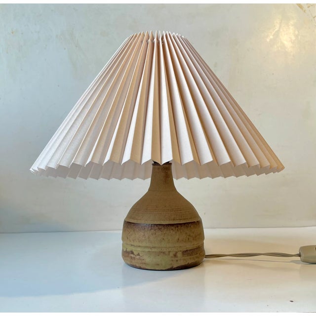 Stylish mallet shaped stoneware table lamp with fluted beige Danish shade. The base exhibits delicate earthy glazes in...