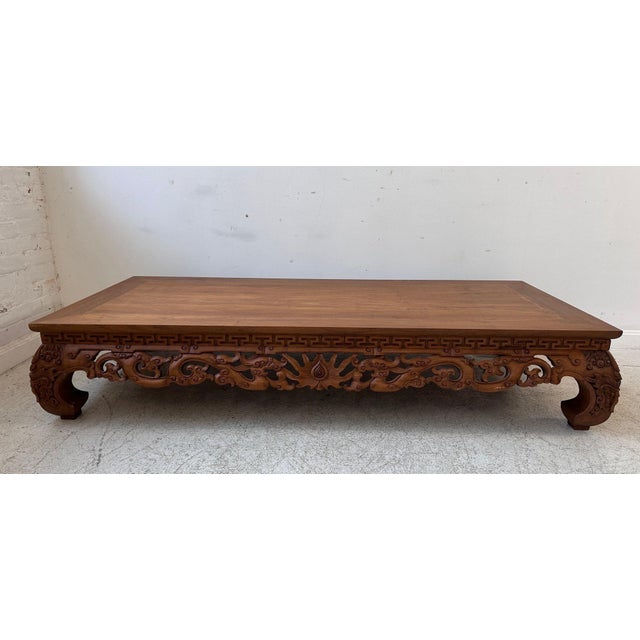 A low, rectangular Ming Dynasty style elm wood coffee table in a warm honey-brown finish with a plain rectangular top...