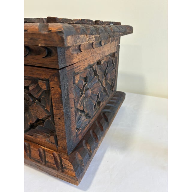 A substantial vintage wooden trunk featuring beautifully executed hand-carved floral motifs on the lid and all visible...