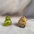 A pair of handmade tiny owls. One is glazed green and the other is painted. The tiny green one is signed on the bottom....