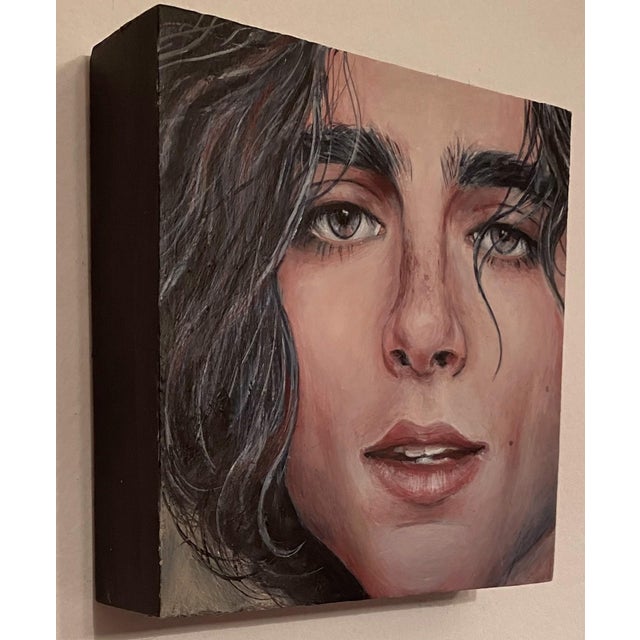 This intimate portrait captures a young man's face with striking detail, emphasizing his expressive eyes and tousled hair....