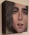 This intimate portrait captures a young man's face with striking detail, emphasizing his expressive eyes and tousled hair....