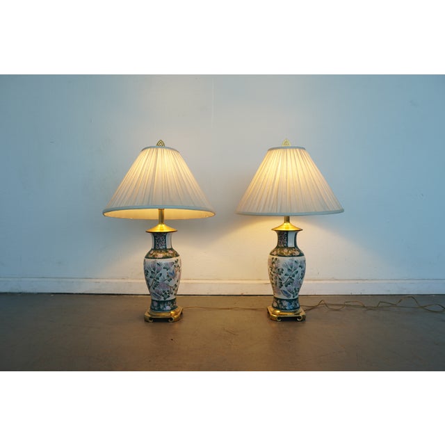 This vintage pair of porcelain table lamps reflects classic chinoiserie influence, likely dating to the late 20th century,...