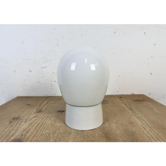 Vintage industrial ceiling or wall light made in former Czechoslivakia during the 1970s. It features a white porcelain...