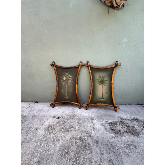 A pair of vintage paintings on wood board depicting tropical palm trees in lush greens and golden light, each framed in...