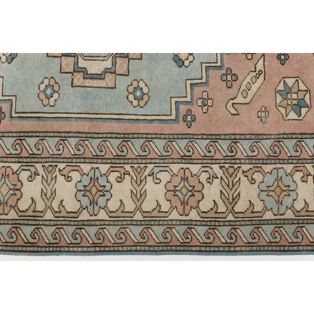 Elevate your home decor with this beautiful, handwoven vintage Turkish area rug. Featuring a delicate harmony of soft pink...