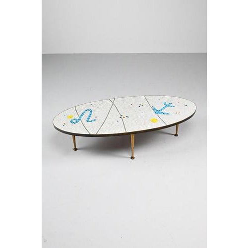 50’s Mosaic side table made of glass tiles in white and with bright colored figures. The top has a brass edge. We found...