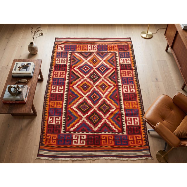 A handwoven Maimana kilim from northern Afghanistan in a full palette of madder red, burnt orange, indigo blue, ivory and...