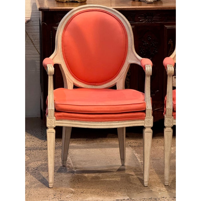 Pair of vintage painted French armchairs with oval backs in molded cream painted frames. The padded arms end in scrolled...