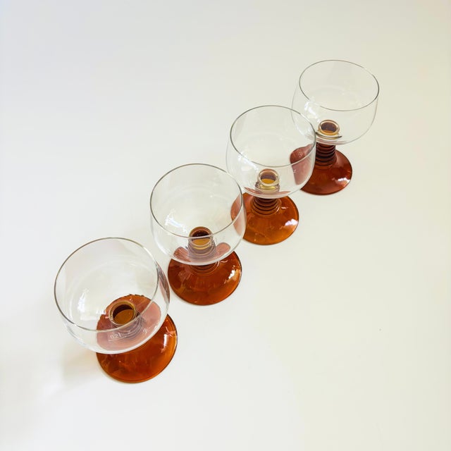A set of 4 vintage German roemer wine glasses. Each with a clear coupe shaped top and classic ribbed stems in an amber...