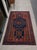 This is a mid-century hand knotted wool rug featuring a deep indigo field, madder red border, and bold geometric tribal...