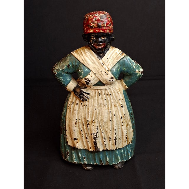 This authentic early 20th-century cast iron doorstop depicts a traditional domestic African American woman figure rendered...