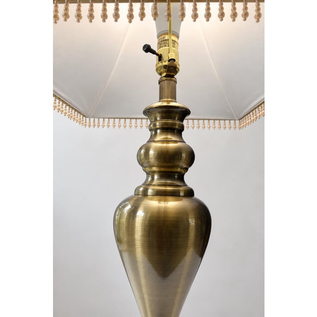 Elegant vintage table lamp featuring a sculptural brass-tone metal base with a beautifully shaped traditional silhouette....
