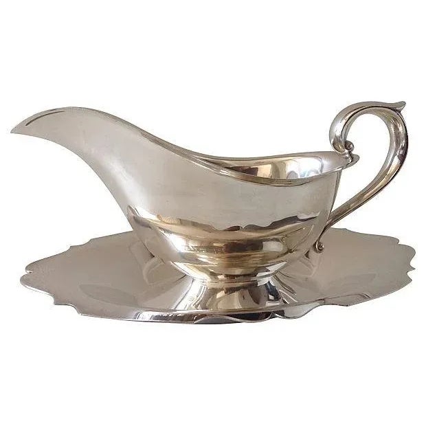 1970's; Silverplate gravy boat with attached scalloped edge under plate. Marked "Newport," Pattern name by the Gorham...
