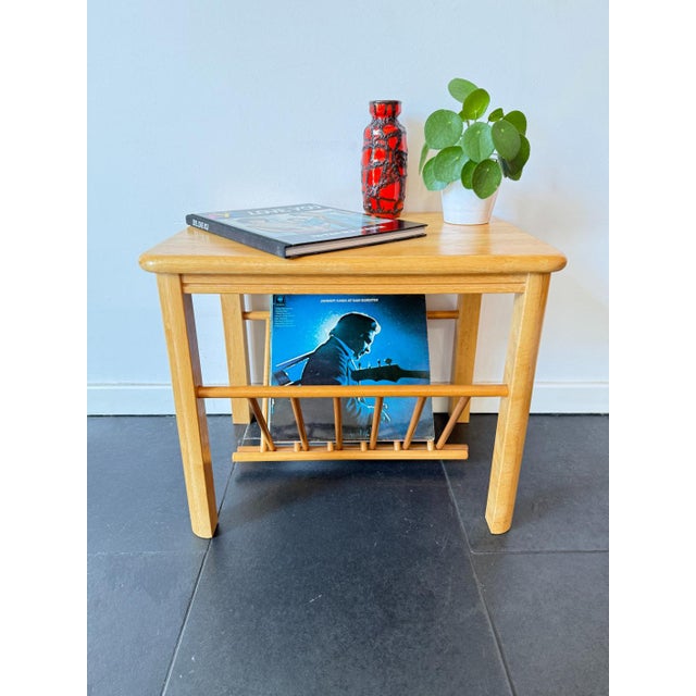This vintage wooden side table with integrated magazine rack reflects a clean mid-century modern style, combining...