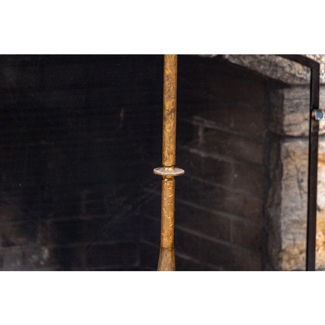 A tall, gilt iron floor candle stand in a striking medieval style with a crown-shaped basket of leafy fronds over a rope...