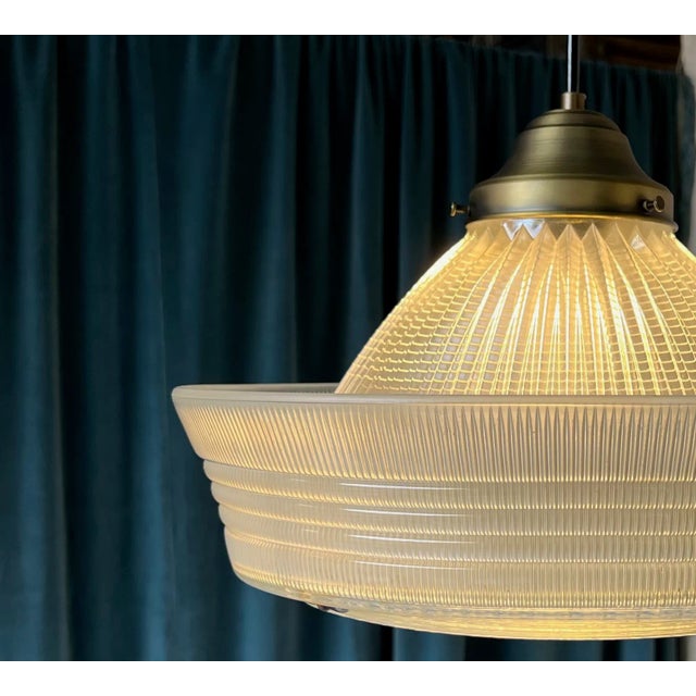A striking mid-century American pendant light featuring a substantial molded glass shade with a distinctive combination of...