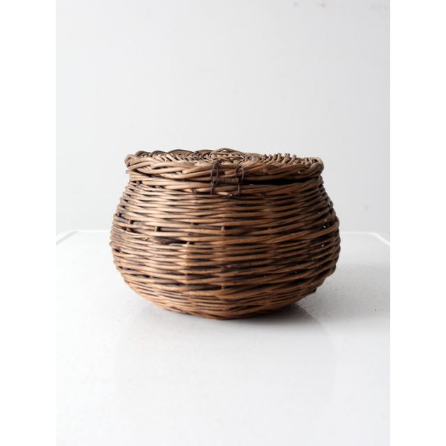 This antique wicker basket features a hinged lid and a classic round shape. Its primitive style and natural texture make...