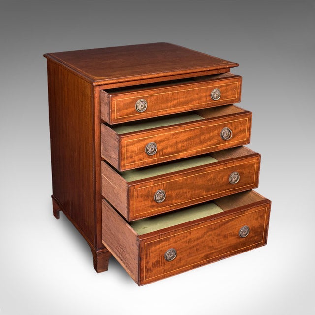 This is an antique bedroom chest of drawers. An English, mahogany and boxwood inlaid squat tallboy in Georgian revival...
