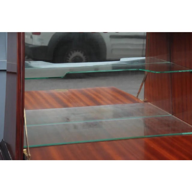 This is a pair of cabinets by Paolo Buffa in mahogany and brass. It has a large flap door that hides an elegant mirrored...