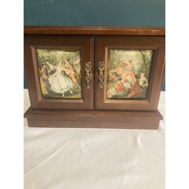 A beautiful vintage finds wooden jewelry box featuring double doors with painted romantic scene panels and ornate brass-...