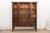 Four paneled doors open to reveal a run of shelves and three interior drawers, framed in a dark lacquer finish accented...