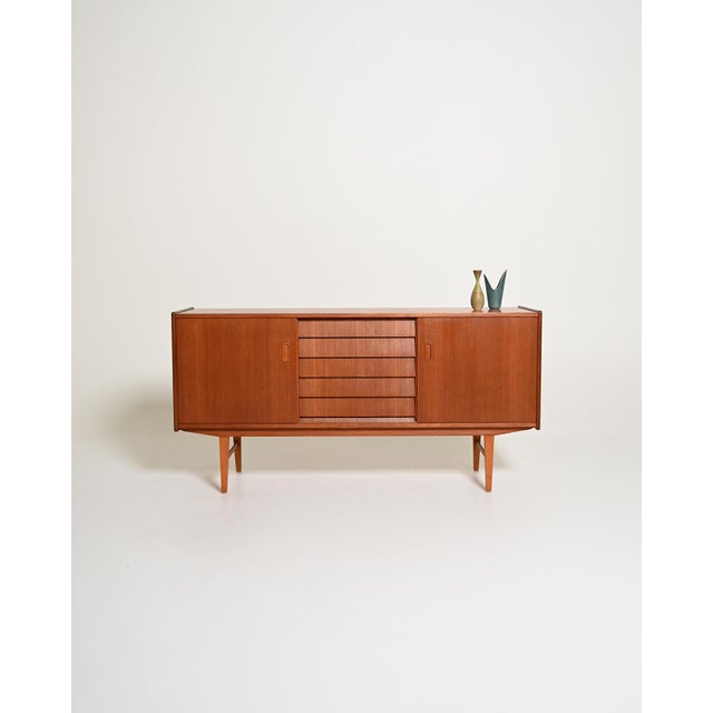 Teak sideboard with two sliding doors, a central compartment with five drawers, and internal shelves. Scandinavian design,...