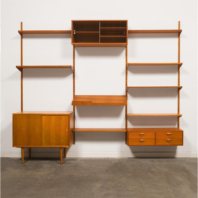 A beautiful 1960s Danish Mid-Century teak wall-mounted system with adjustable shelves and cabinets. This innovative mid-...