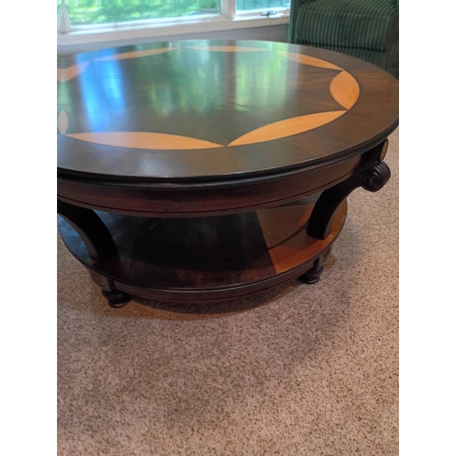 Professionally refinished elegant French-inspired round coffee table features striking two-tone wood with a starburst...