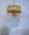 This ornate gold‑tone chandelier features a sculpted metal crown accented with elongated teardrop crystals and layered...