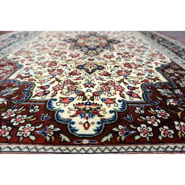 Handmade vintage Persian Qum rug in very busy floral design with natural colors. The rug has been made in silk. It is is...