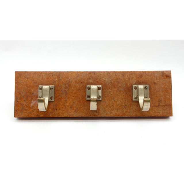 Three aluminum coat or hat rack with a textured wooden base. The original mounting screws are not available. This item was...