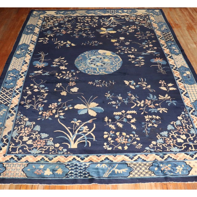 an early 20th Century hand-knotted one of a kind Chinese Peking Carpet with a floral design on a navy field. Professionaly...