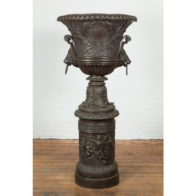 A custom made tall and large lost wax cast bronze urn on pedestal adorned with lion head handles. Created with the...